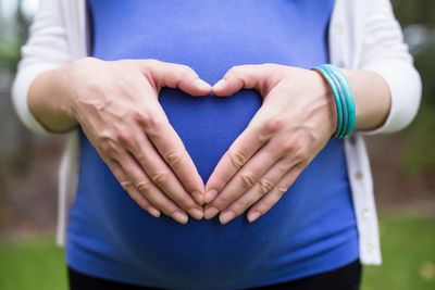 Prenatal care — pregnant woman making a heart shape with her hands over her belly